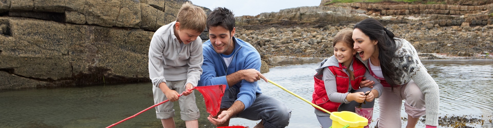 young family at beach fishing in rock pools